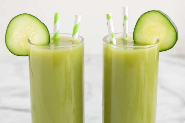 Deux verres de jus de concombre et de céleri avec des rondelles de concombre et des pailles.