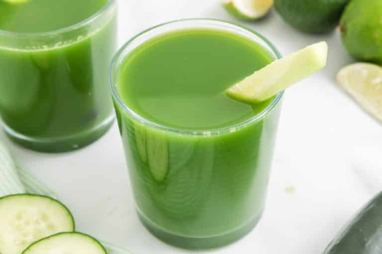 Vue du dessus d'un verre de jus de concombre avec un quartier de citron vert sur le bord.