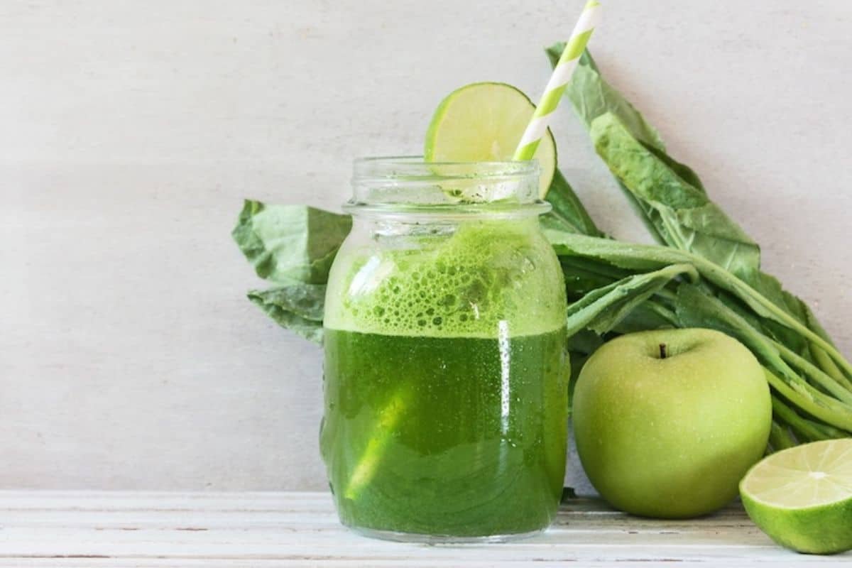 un verre de jus vert de pissenlit avec une paille.