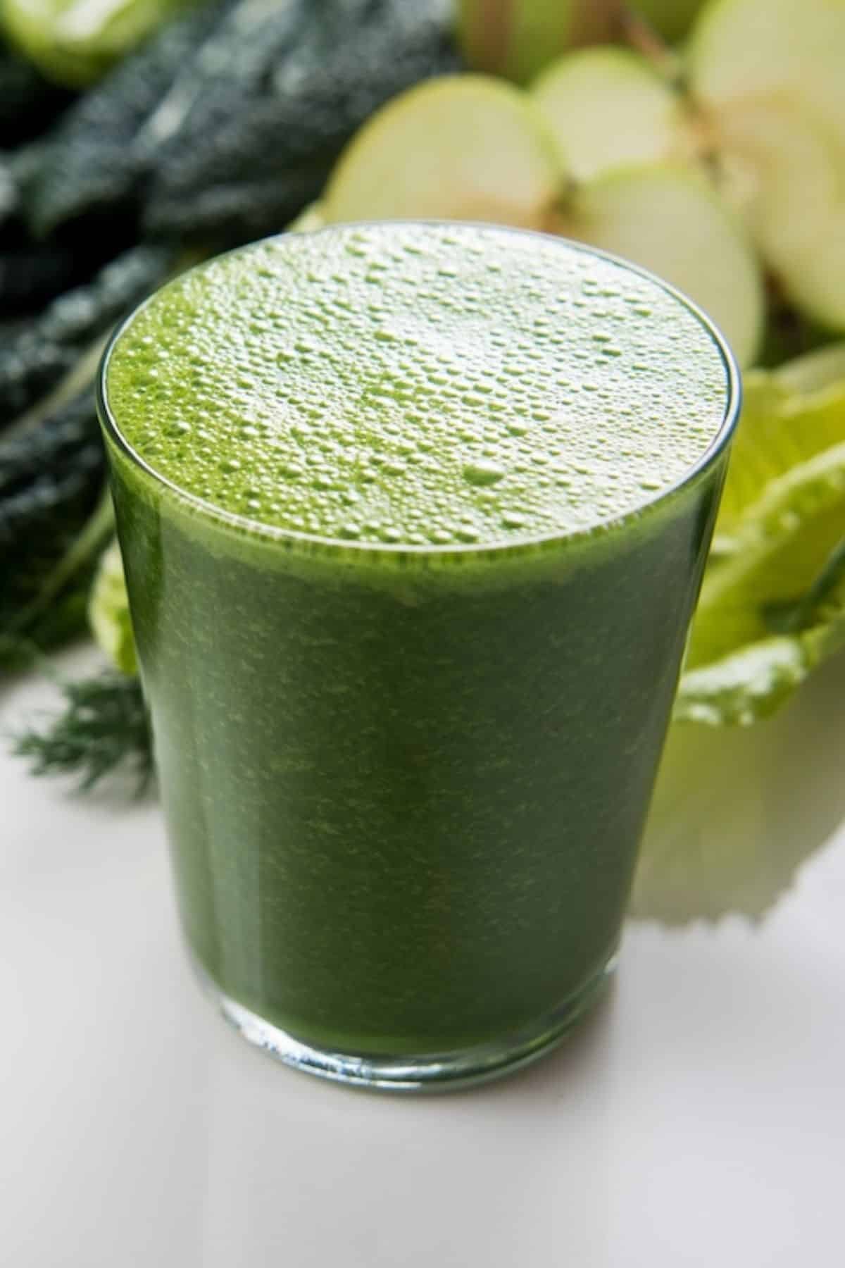 Un verre de jus vert sur une table.