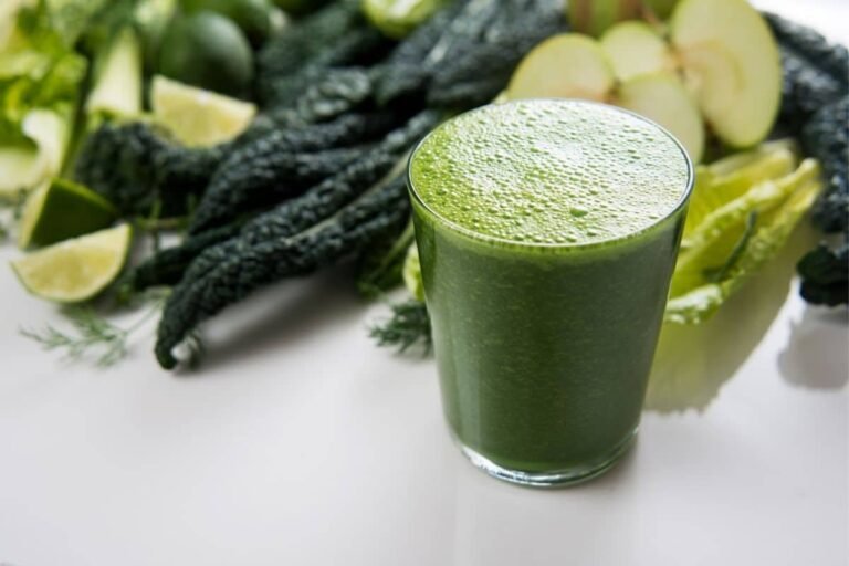 Un verre de jus vert sur un comptoir blanc.