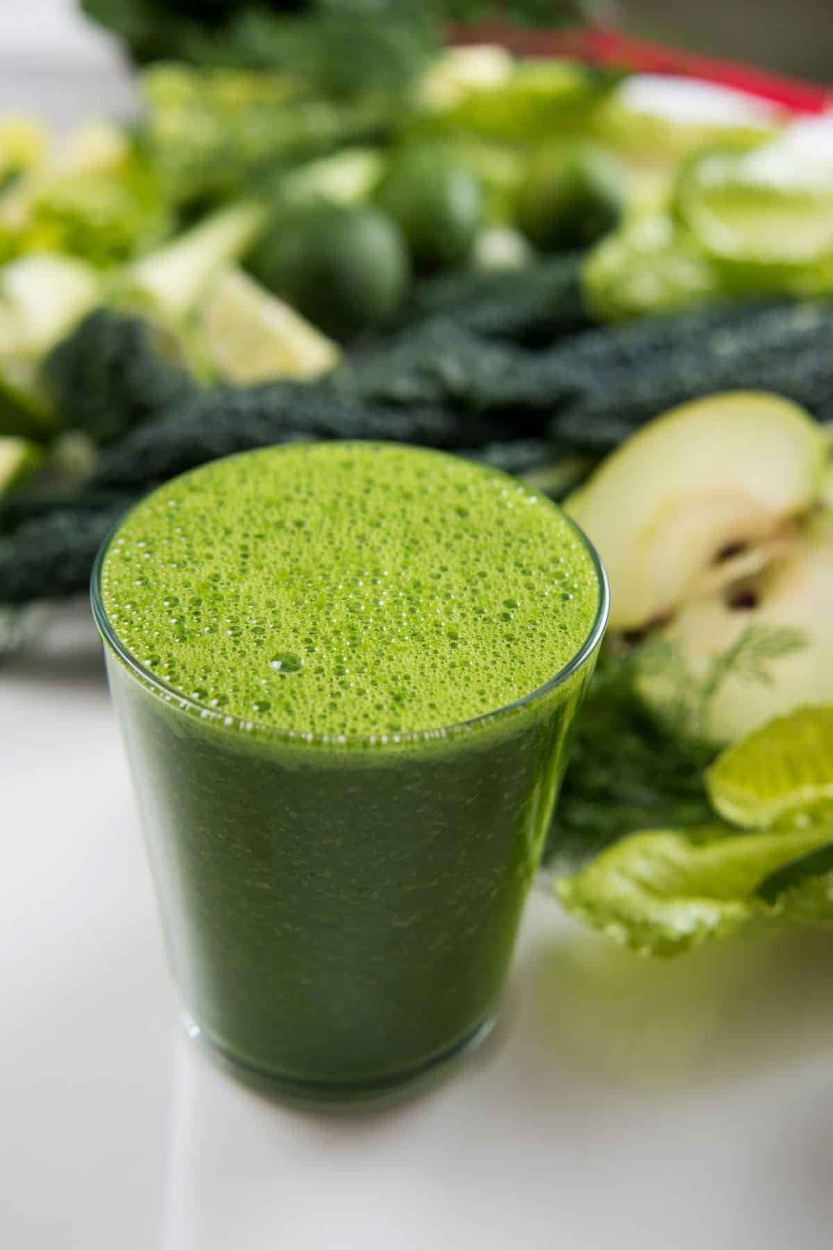 Un verre de jus vert sur un comptoir blanc.