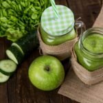 Green Vegetable Detox Juice green smoothie made with apple, cucumber, and lettuce served in mason jars on wooden background.