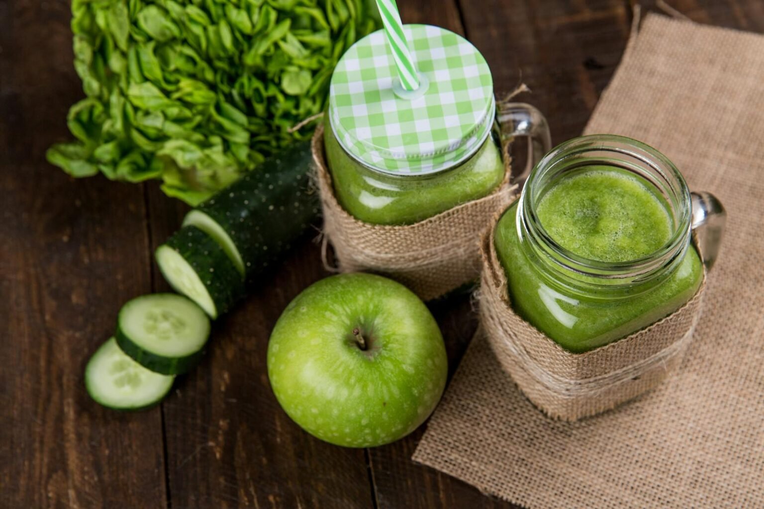 Green Vegetable Detox Juice green smoothie made with apple, cucumber, and lettuce served in mason jars on wooden background.