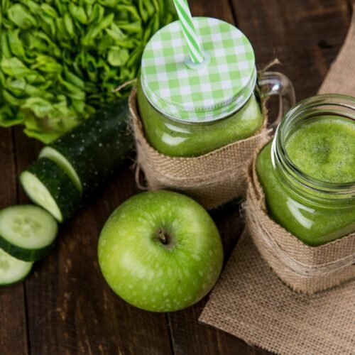 Green Vegetable Detox Juice green smoothie made with apple, cucumber, and lettuce served in mason jars on wooden background.