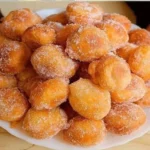 A plate of perfectly mini doughnuts topped with colorful sprinkles.