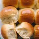 Freshly baked soft and fluffy dinner rolls on a wooden table