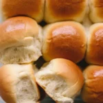 Freshly baked soft and fluffy dinner rolls on a wooden table