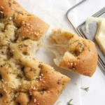 Homemade Garlic and Herb Focaccia Bread topped with garlic and fresh herbs.