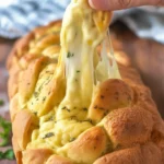 Cheesy pull-apart bread topped with garlic and melted cheese, served warm.