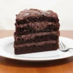 Delicious gluten-free chocolate cake served on a plate with chocolate frosting.