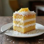 Slice of Pineapple Coconut Dream Cake topped with coconut flakes and pineapple slices