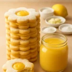 Lemon sandwich cookies with sandy dough and lemon cream filling on a plate.