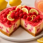 Raspberry lemonade cheesecake slice garnished with fresh raspberries and lemon.